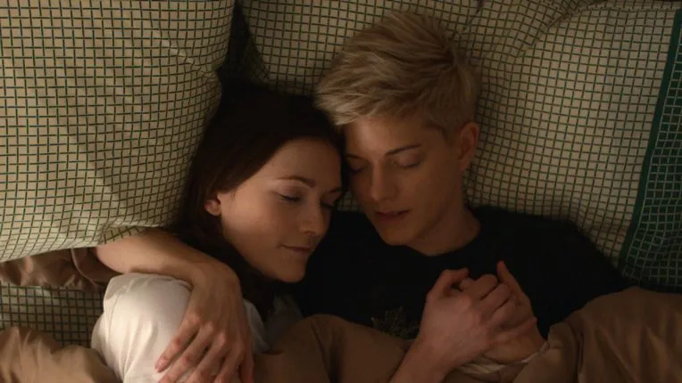 Charlotte Ritchie and Mae Martin embrace in bed as Mae and George in Feel Good