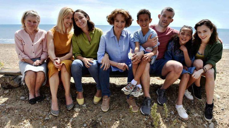 Imelda Staunton, Russell Tovey and the cast of Flesh and Beach sit on a beach bench in the sunshine